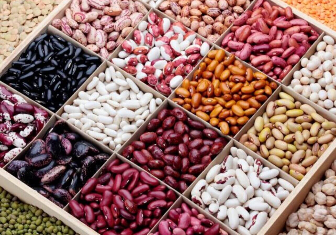 A wooden box filled with different types of beans.